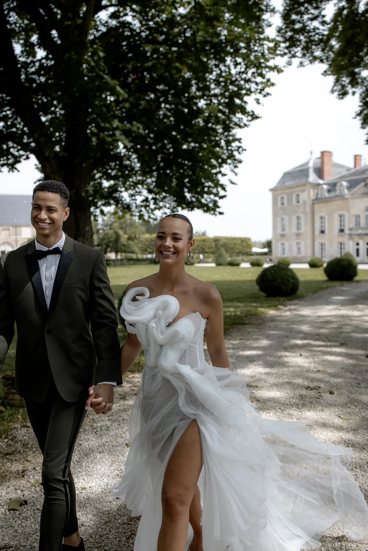Happy bridal couple during couple shoot in park of Chateau de Varennes with flowing wedding gown